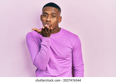Young Black Man Wearing Casual Pink Sweater Looking At The Camera Blowing A Kiss With Hand On Air Being Lovely And Sexy. Love Expression. 
