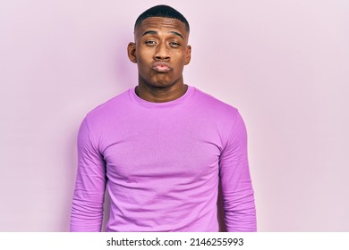 Young Black Man Wearing Casual Pink Sweater Looking At The Camera Blowing A Kiss On Air Being Lovely And Sexy. Love Expression. 