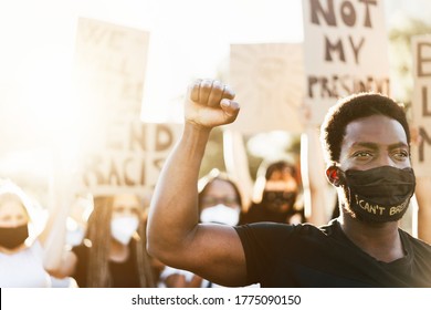 Young black man wearing face mask during equal rights protest - Concept of demonstrators on road for Black Lives Matter and I Can't Breathe campaign - Focus on man's face