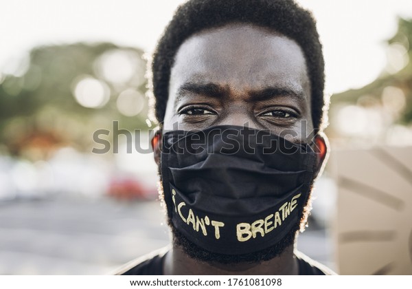 Young black man wearing face\
mask during equal rights protest - Concept of demonstrators on road\
for Black Lives Matter and I Can\'t Breathe campaign - Focus on\
eyes