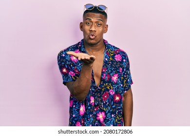Young Black Man Wearing Hawaiian Shirt And Sunglasses Looking At The Camera Blowing A Kiss With Hand On Air Being Lovely And Sexy. Love Expression. 