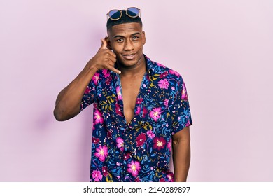 Young Black Man Wearing Hawaiian Shirt And Sunglasses Smiling Doing Phone Gesture With Hand And Fingers Like Talking On The Telephone. Communicating Concepts. 