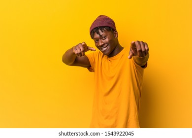 Young Black Man Wearing Rastas Over Yellow Background Cheerful Smiles Pointing To Front.