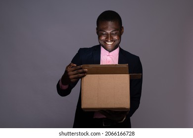 Young Black Man Wearing A Suit Opening A Box