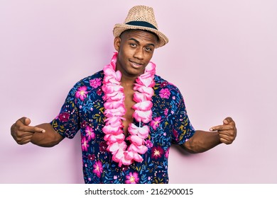 Young Black Man Wearing Summer Shirt And Hawaiian Lei Looking Confident With Smile On Face, Pointing Oneself With Fingers Proud And Happy. 