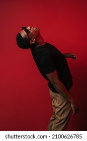 Young Black Man Wearing Sunglasses Screaming And Looking Upward Isolated Over Red Wall