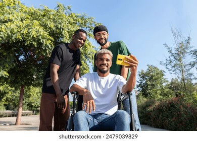 Young black man in a wheelchair using phone taking selfie together with male friends outdoors. Friendship and technology concept. - Powered by Shutterstock