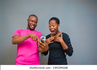 young black man and woman happily looking at something surprising on their phone