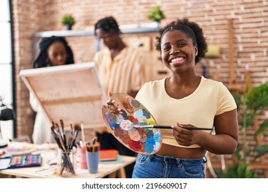 Young Black Painter Woman At Art Studio Holding Palette Smiling With A Happy And Cool Smile On Face. Showing Teeth. 