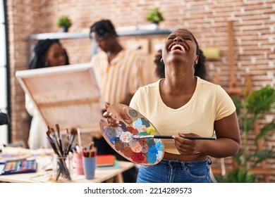 Young Black Painter Woman At Art Studio Holding Palette Smiling And Laughing Hard Out Loud Because Funny Crazy Joke. 