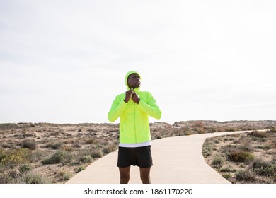 Young Black Runner Adjusts His Yellow Jacket And Prepares To Train.