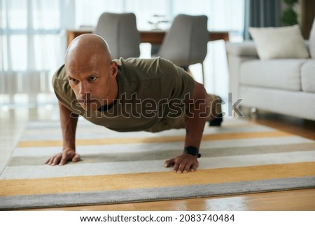 Young black soldier doing push-ups while working out in the living room.