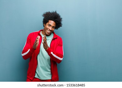 Young Black Sports Man Feeling Happy And Successful, Smiling And Clapping Hands, Saying Congratulations With An Applause Against Grunge Wall