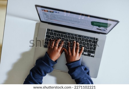 Young black student learning to code in a computer science classroom. High angle view of a kid typing on a laptop as he works on a programming exercise in a digital literacy lesson.