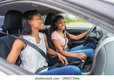 A Young black teenage driver seated in her new car with her mother