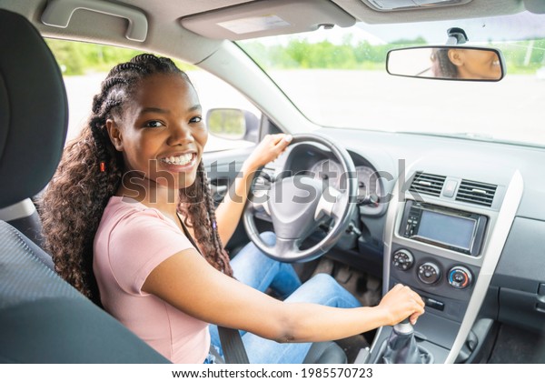 A Young\
black teenage driver seated in her new\
car