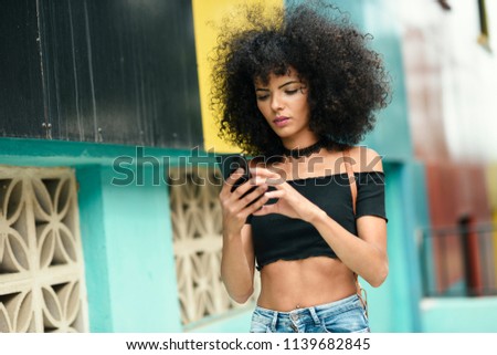 Similar – Frau mit Afro-Haaren auf der Straße, die ein Smartphone hält.