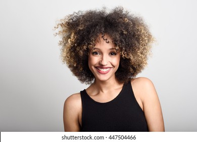 Young black woman with afro hairstyle smiling. Girl wearing black dress. Studio shot. - Powered by Shutterstock