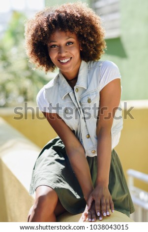 blYoung black woman, afro hairstyle, smiling outdoors