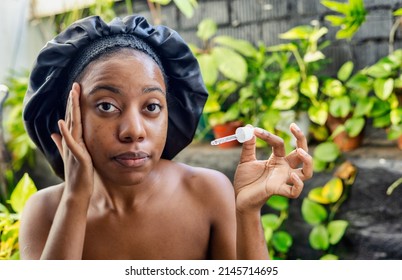 Young Black Woman Woman Applying Hyaluronic Serum From Dropper. Skincare Concept.