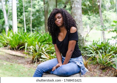 A Young Black Woman Between 20 And 30 Years Old Sitting Reading A Book Alone, In A Park