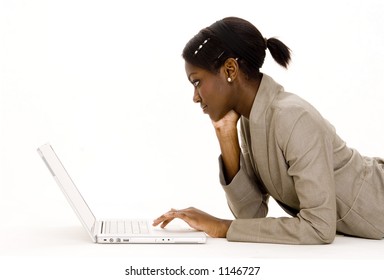 A Young Black Woman In Business Suit Using A Laptop Computer On The Floor