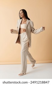 A young black woman in a cream suit walks confidently on a beige background.