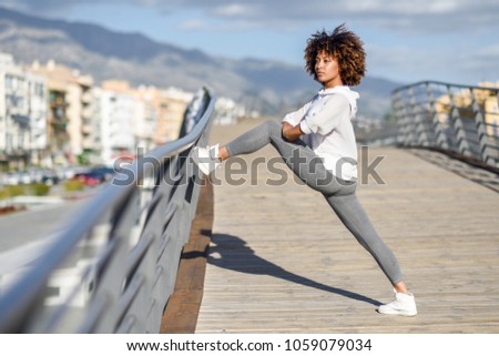 Young black woman doing stretching after running outdoors