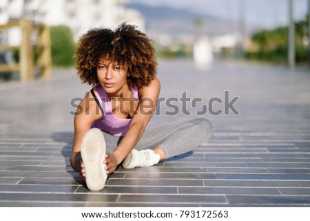 Young black woman doing stretching after running outdoors