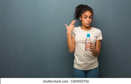 Young black woman doing a suicide gesture. She is holding a water bottle.