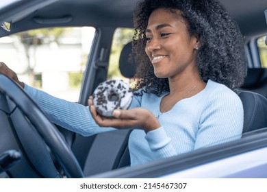 A Young Black Woman Driving And Eating