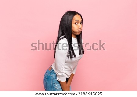 young black woman with a goofy, crazy, surprised expression, puffing cheeks, feeling stuffed, fat and full of food