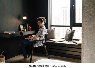 Young Black Woman In Headphones Working With Laptop At Home