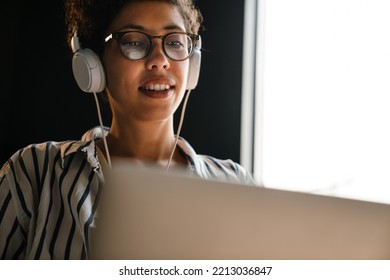 Young Black Woman In Headphones Working With Laptop At Home