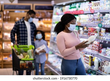 Young Black Woman With Her Family Purchasing Dairy Products At Modern Supermarket During Covid Quarantine, Copy Space. Millennial Consumers Shopping For Food At Huge Mall