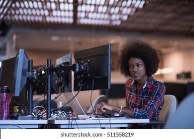 young black woman at her workplace in modern office  relaxing and working on laptop computer with dual monitor screen