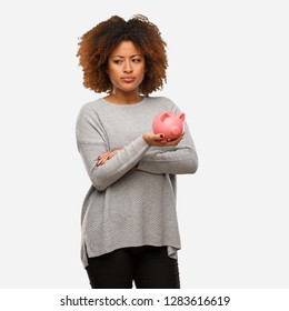 Young Black Woman Holding Piggy Bank Looking Straight Ahead