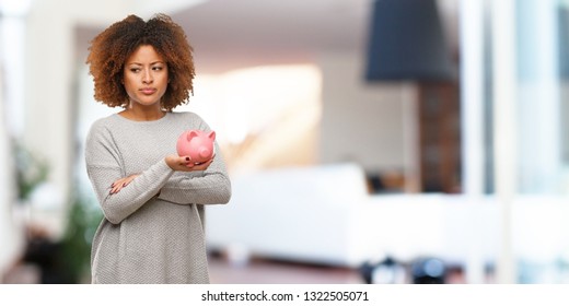 Young Black Woman Holding Piggy Bank Looking Straight Ahead