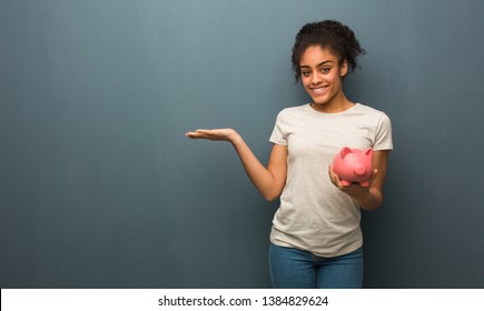 Young Black Woman Holding Something With Hand. She Is Holding A Piggy Bank.