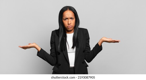 Young Black Woman Looking Puzzled, Confused And Stressed, Wondering Between Different Options, Feeling Uncertain. Business Concept