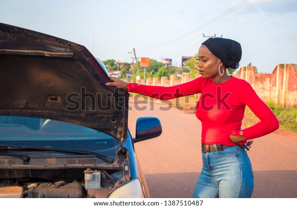 young black woman looking worried because her car\
broke down