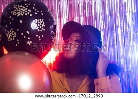 Young black woman looks happy while spend time in night club. Birthday party and nightlife concept.