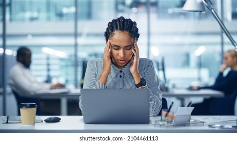 Young Black Woman Office Worker Uses Laptop, Feels Sudden Burst of Pain, Headache, Migraine. Overworked Accountant Feeling Project Pressure, Stress, Massages Her Head, Temples. Front View Portrait - Shutterstock ID 2104461113