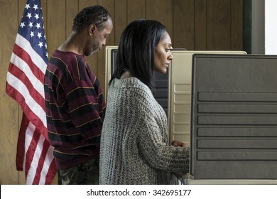 Young Black Woman And Older Black Male Voting In A Booth