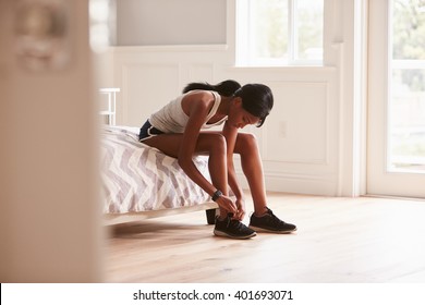 Young black woman ready for exercising tying her sports shoe - Powered by Shutterstock
