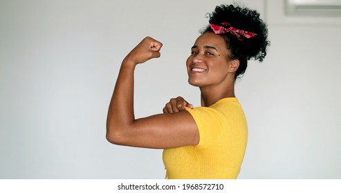 Young black woman showing muscle, We Can Do It symbolic feminist stand