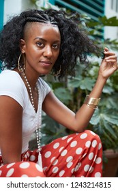 Young Black Woman Sitting Outdoors And Touching Her Hair