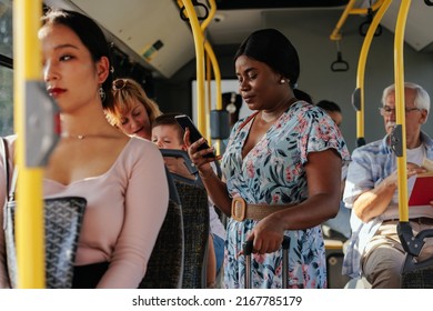 A Young Black Woman Is Standing In A Crowded Bus And Texting.