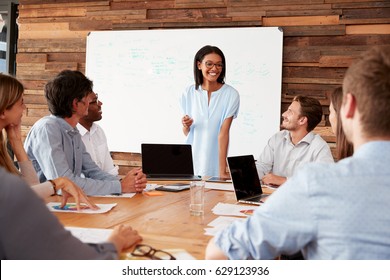 Young Black Woman Stands Addressing Colleagues At A Meeting