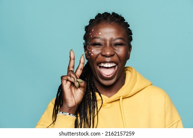 Young Black Woman With Stickers On Her Face Showing Peace Sign Isolated Over Blue Background